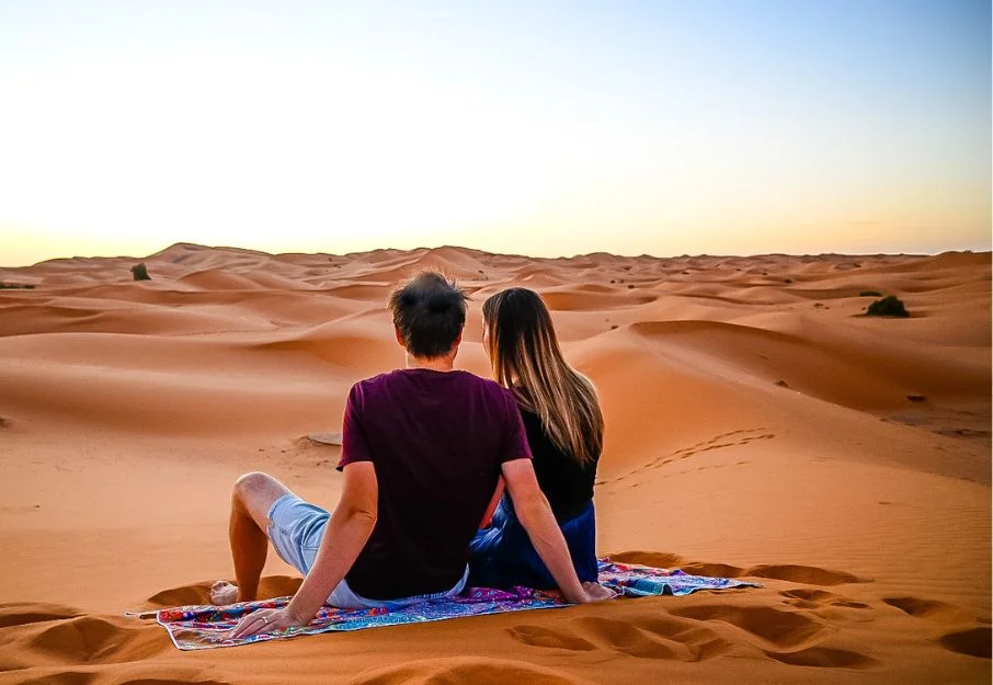 couple enjoying Sahara desert sunrise