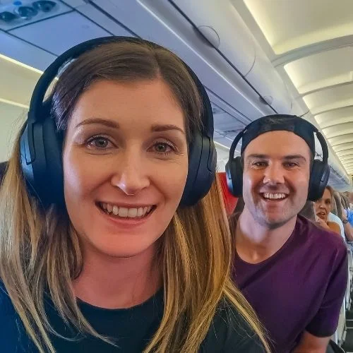 man and woman smiling on plane with headphones