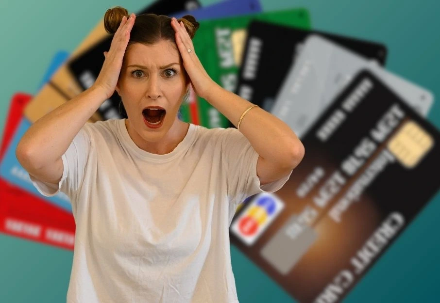 Credit cards in background and woman with hands on head in foreground