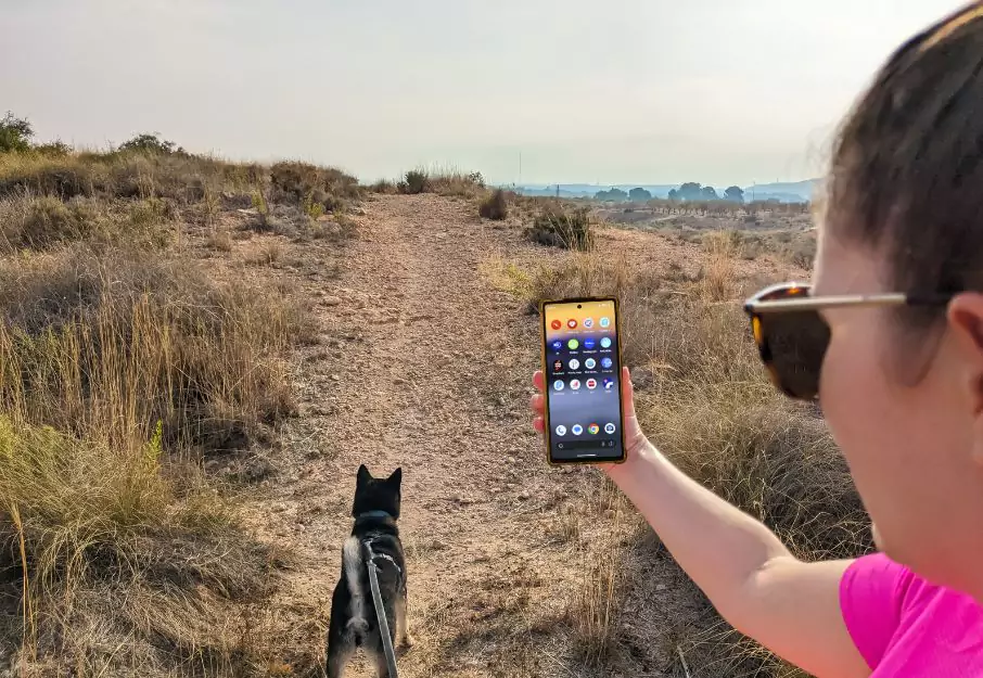 Lady hiking with dog while showing phone apps