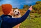 Man pointing to Lakes District view with cute Golden Retriever looking happy.