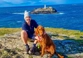Man sitting with brown dog on coastal walk in Cornwall, UK