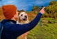 Man pointing at a lake view with a cute Golden Retriever looking on with a grin