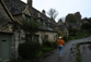 Woman walking past the old brick buildings in a Cotswolds town